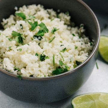 Side view, a bowl of cauliflower rice seasoned with cilantro and lime.