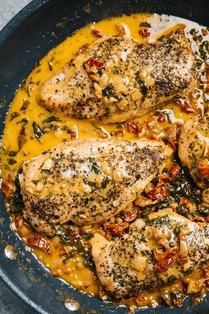 Creamy basil chicken with sun dried tomatoes in a skillet.