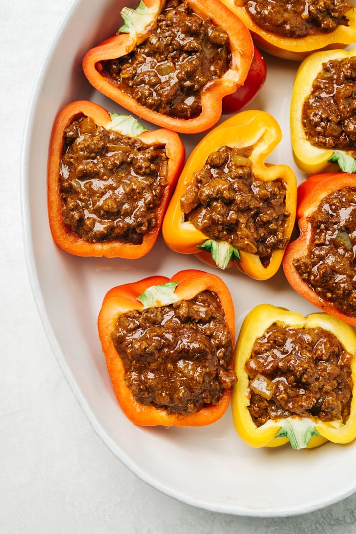 Bell peppers sliced in half and stuffed with taco meat in a casserole dish.
