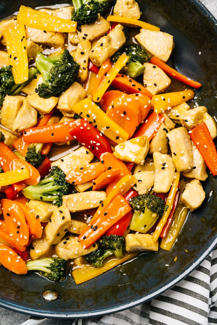 Overhead, healthy chicken stir fry in a skillet with broccoli, carrots, and bell peppers.