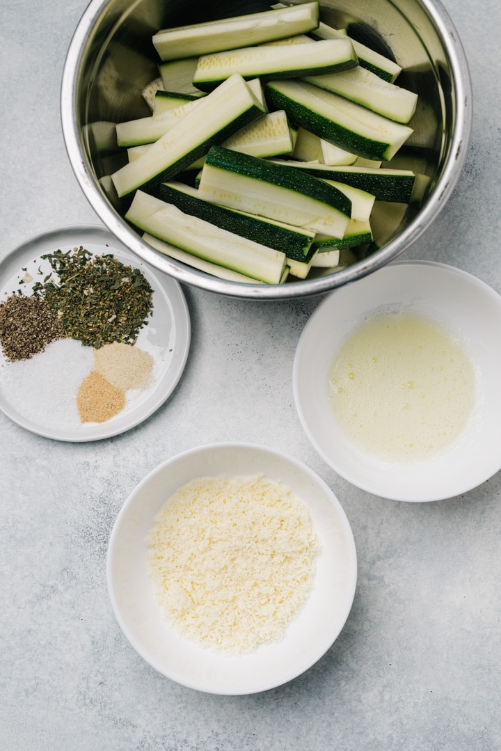 The ingredients for roasted parmesan zucchini on a cement background.