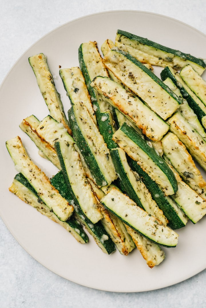 Parmesan roasted zucchini wedges on a tan serving platter.