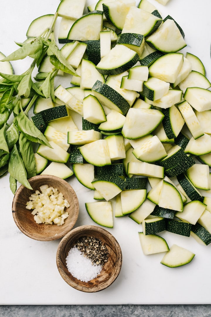 The ingredients for sauteed zucchini arranged on a cutting board. 