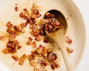 Diced cooked bacon in a skillet.
