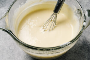 Wet ingredients for healthier cornbread in mixing bowl - greek yogurt, honey, eggs, and olive oil.
