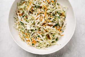 Low carb keto coleslaw with bacon vinaigrette in a large white serving bowl.