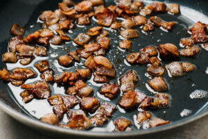 Crisp diced bacon in a skillet.