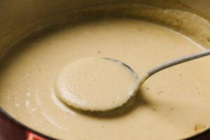Pureed potato soup in a dutch oven with a metal ladle.