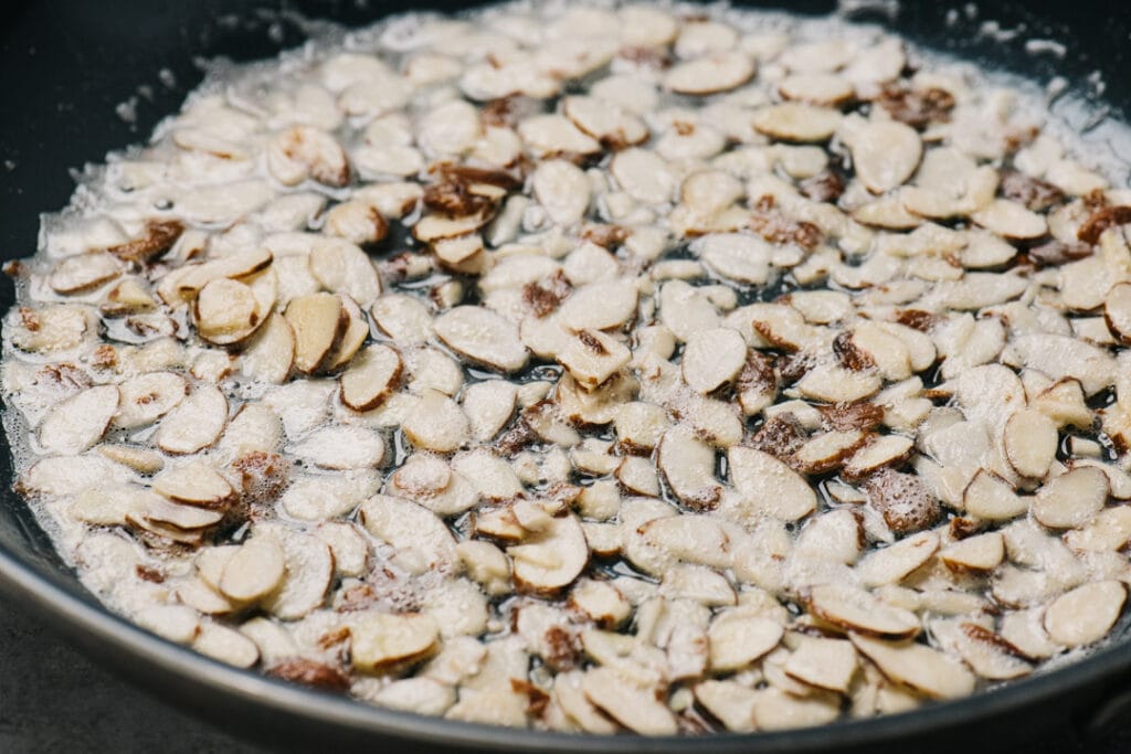 Silvered almonds sauteeing in butter in a skillet.