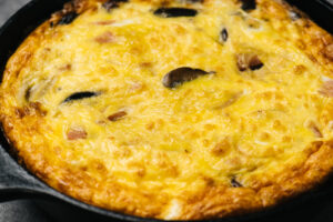 Cooked crustless ham quiche in a cast iron skillet.