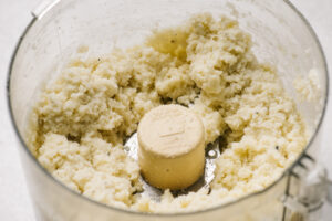 Mashed cauliflower in the bowl of a food processor.