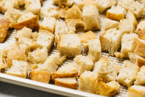 Golden brown sourdough cubes on a baking sheet.