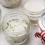 A stack of infused salts packaged in mini mason jars with ribbons.