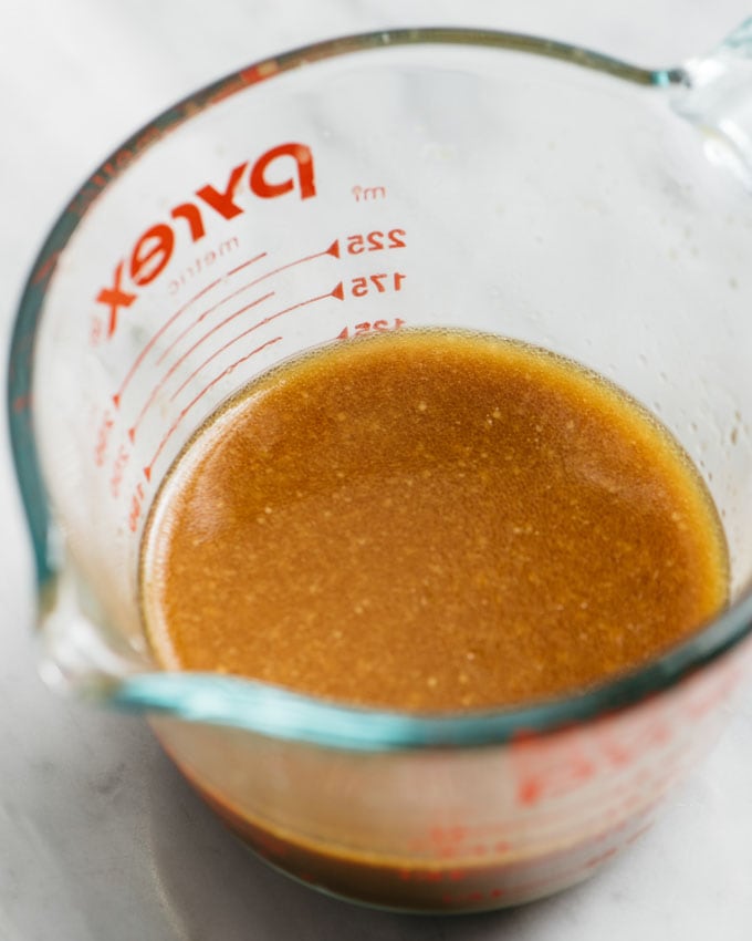 Stir fry sauce in a 1-cup measuring cup on a marble table.