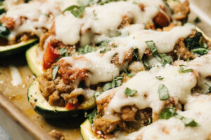 Side view, cooked italian sausage zucchini boats in a casserole dish.
