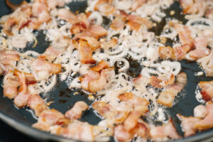 Sauteed shallots and bacon in a skillet.