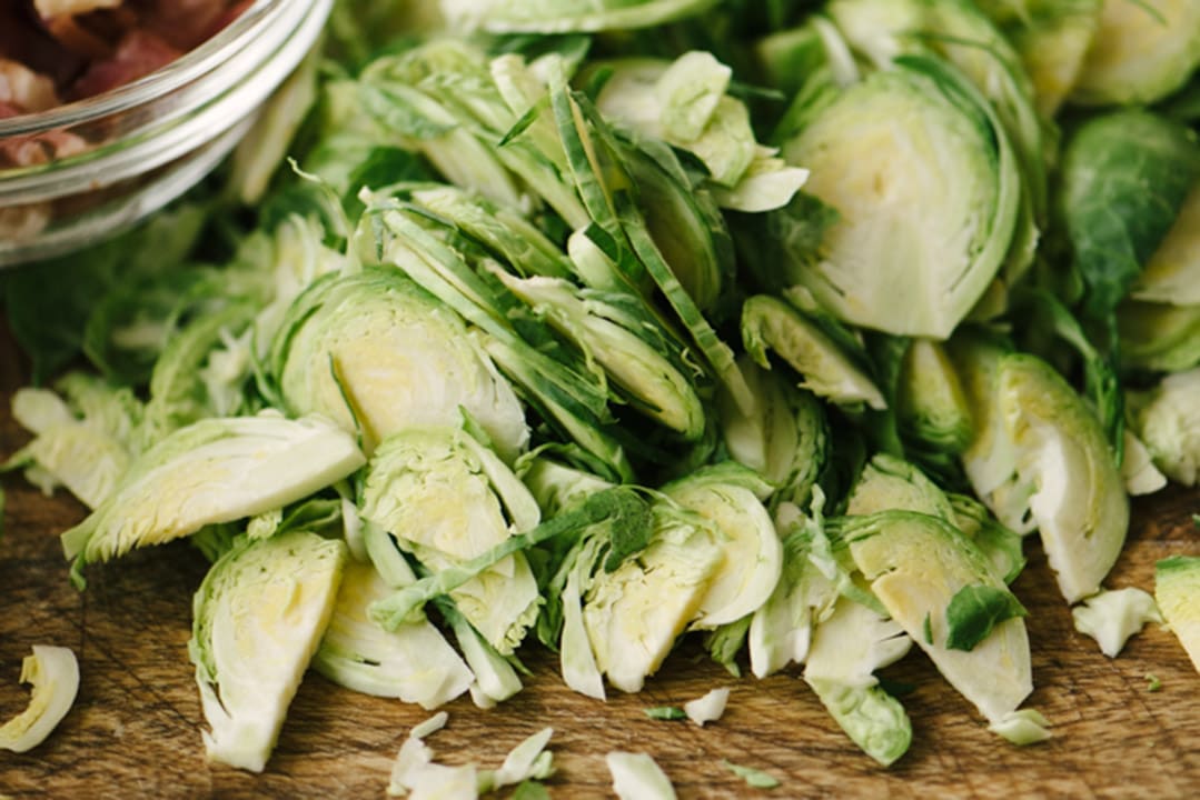 Thinly sliced shaved brussels sprouts on a cutting board.