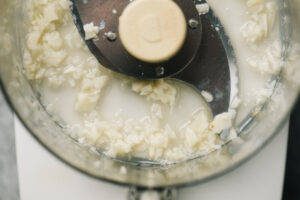 Garlic and lemon juice pulverized in the bowl of a food processor.
