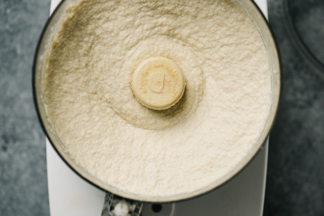 Smooth and creamy cauliflower hummus in the bowl of a food processor.