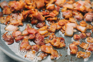 Chopped bacon cooked in a skillet.