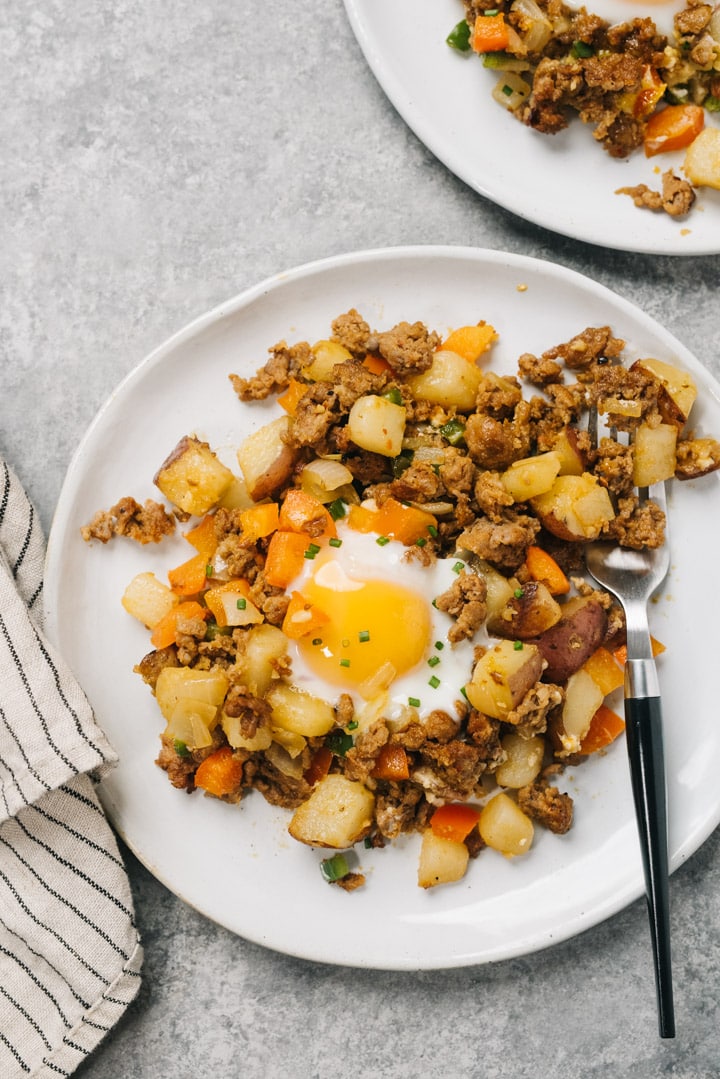 A serving of mexican potato hash on a white plate with a runny egg.