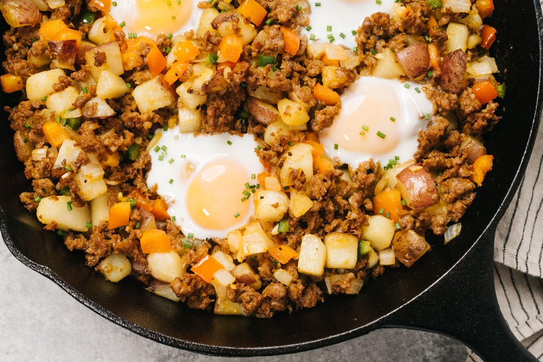 Mexican inspired potato hash in a cast iron skillet with chorizo sausage and runny eggs.