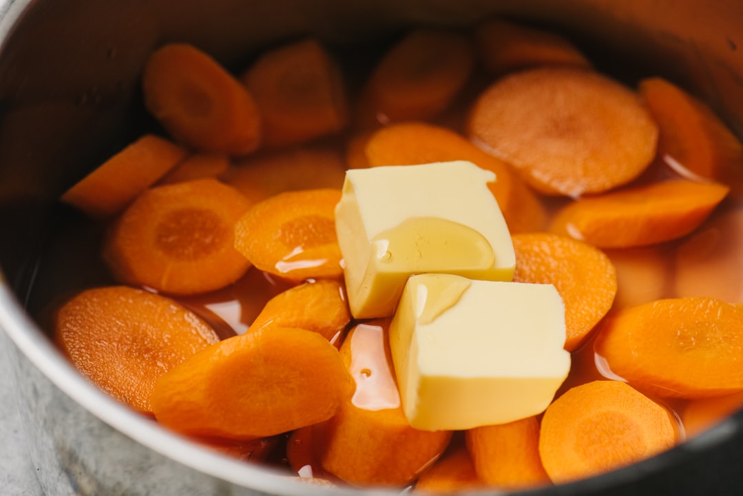 Sliced carrots in a pot with water, cornstarch, butter, honey, and salt.