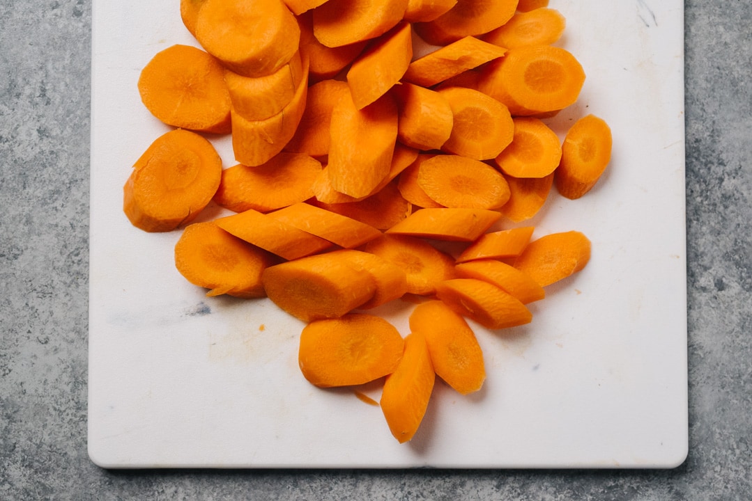 Sliced carrots at an angle on a white cutting board.