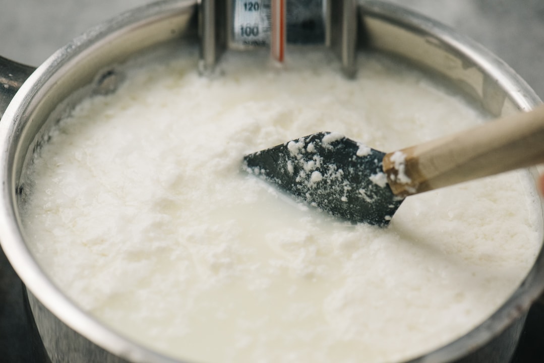 Stirring heated milk with salt and vinegar until curds form.