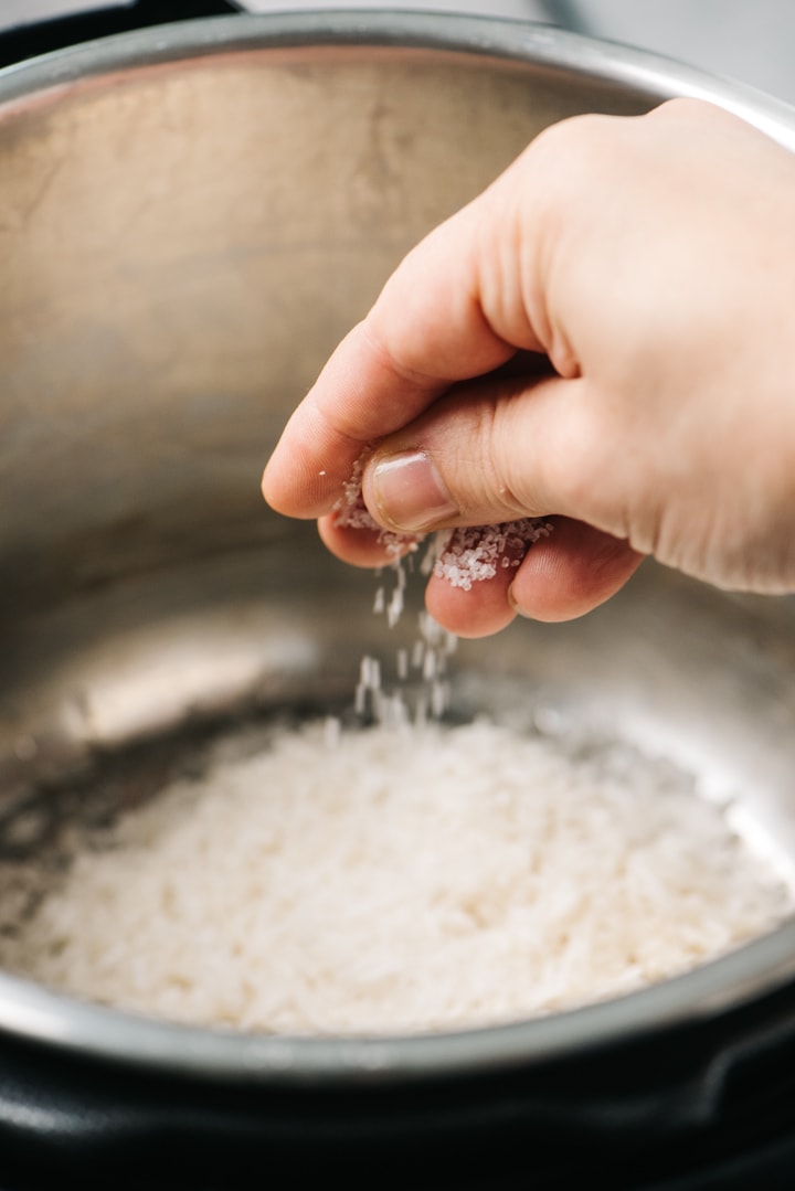 Sprinkling salt over rinsed jasmine rice in an instant pot.
