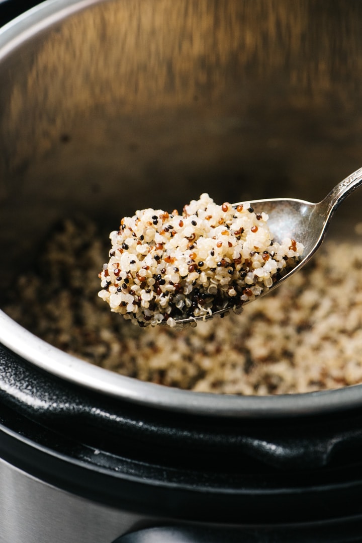A spoonful of pressure cooker quinoa hovering over an instant pot.