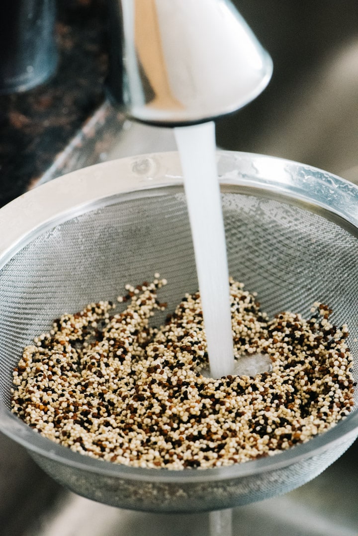 Rinsing quinoa with cool running water from the sink in a fine mesh sieve.