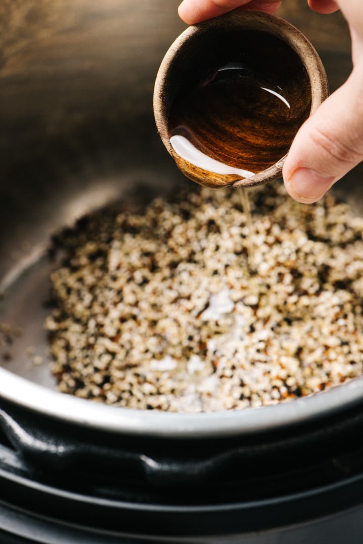 Pouring olive oil over quinoa in an instant pot.