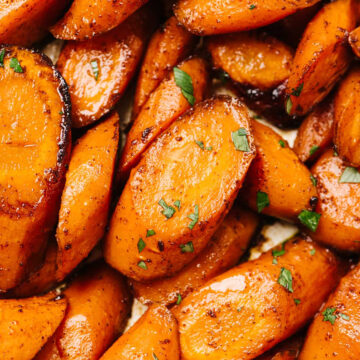 Sliced baked carrots garnished with chopped parsley.