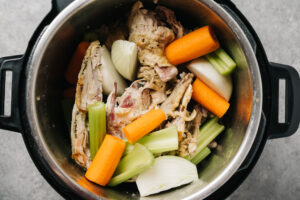 Chicken bones and vegetables (onion, carrot and celery) in an instant pot.