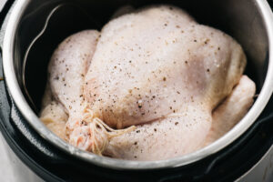 A stuffed and trussed whole chicken on a trivet in an instant pot.