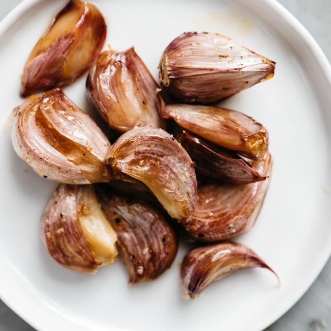 Roasted garlic cloves on a white plate.