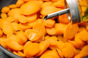 Adding olive oil to steamed carrots.