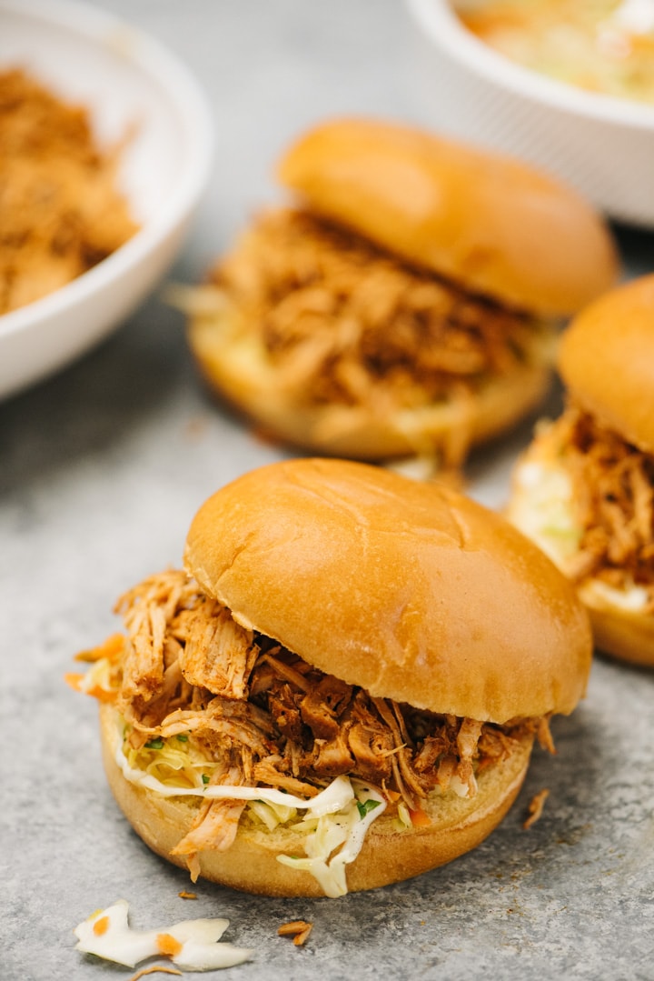Three pulled pork sandwiches with coleslaw on buns.