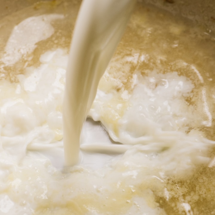 Adding milk to a roux with pasta water to make a creamy pasta sauce.