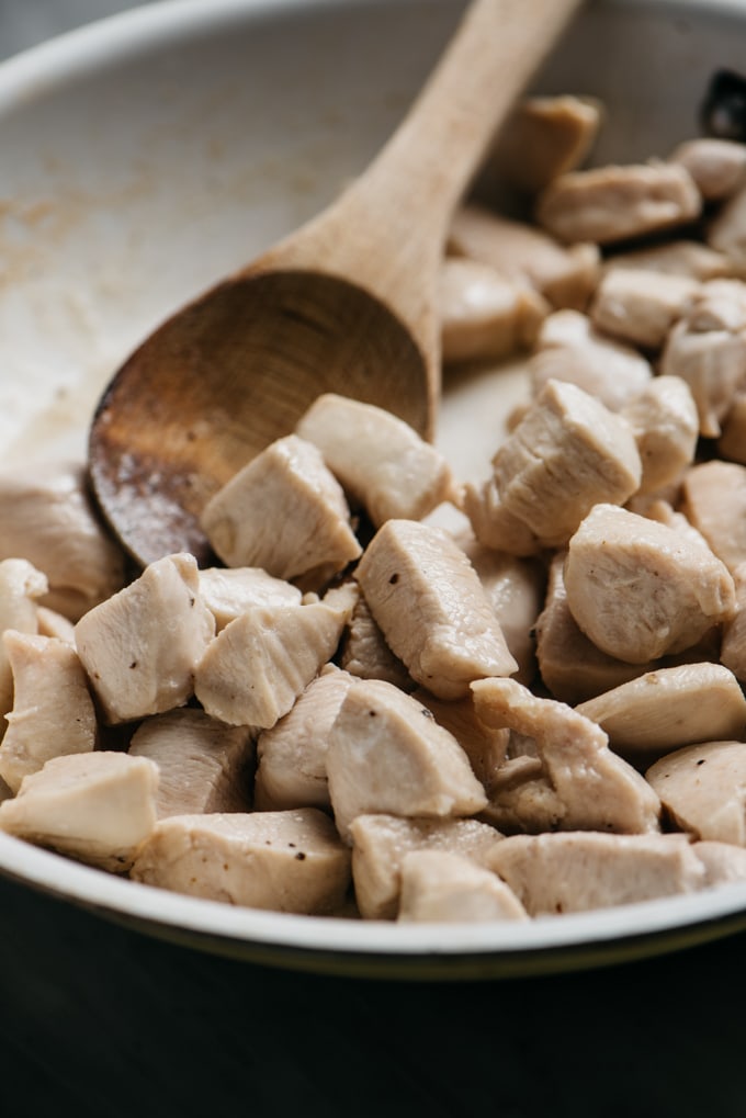 Cubes of chicken breast stir fried in a skillet.
