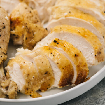 Side view, a carved whole chicken cooked in an instant pot on a white platter.