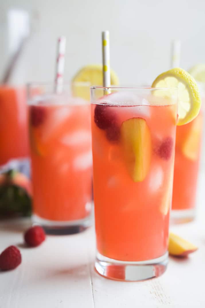 Three glasses of raspberry peach lemonade on a concrete background.