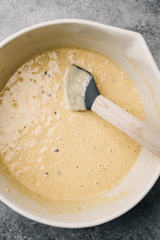 Banana bread pancake batter in a large mixing bowl with a rubber spatula.