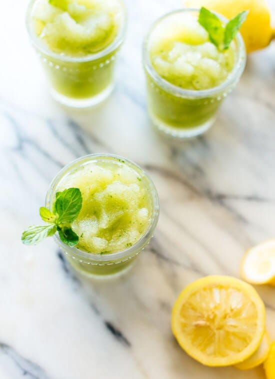 Three glasses of frozen mint lemonade on a marble background.
