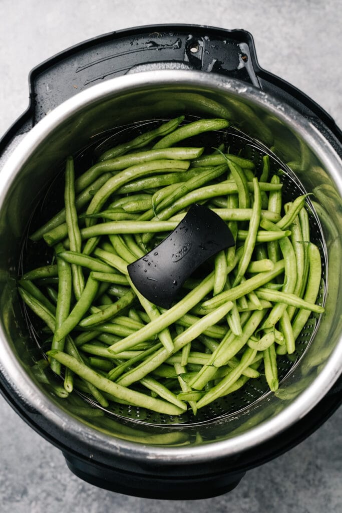 Green beans in a steamer basket inside an instant pot.