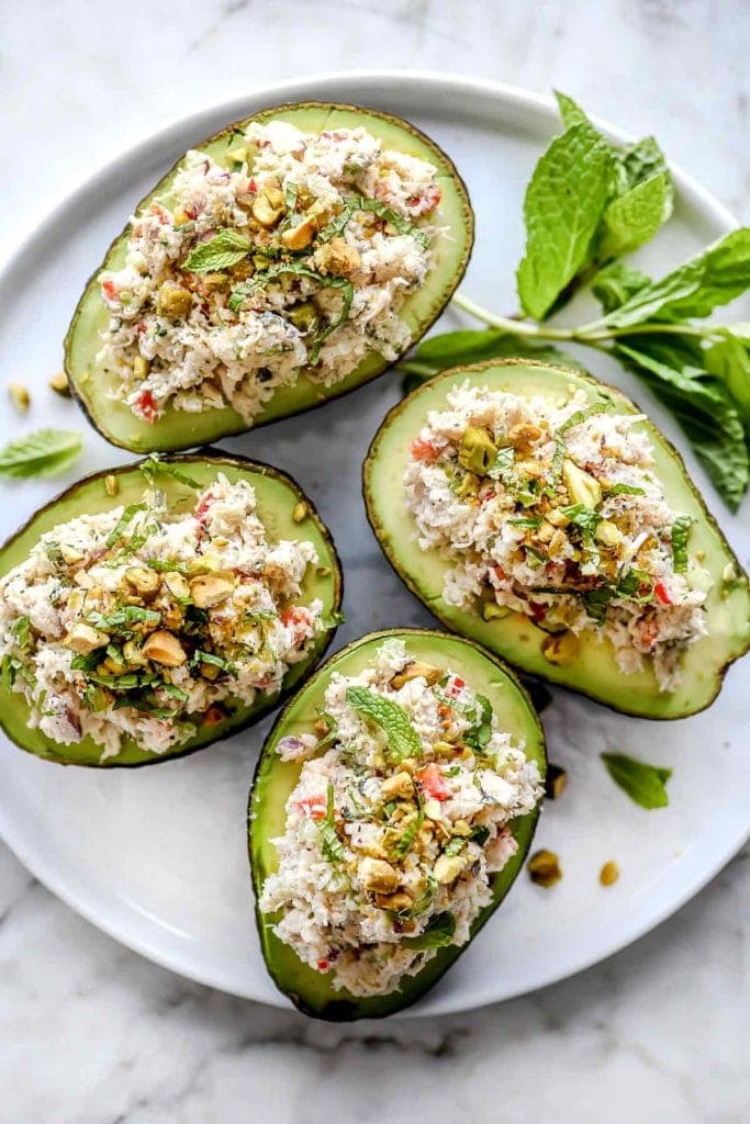 Halved avocados stuffed with crab salad on a white plate.