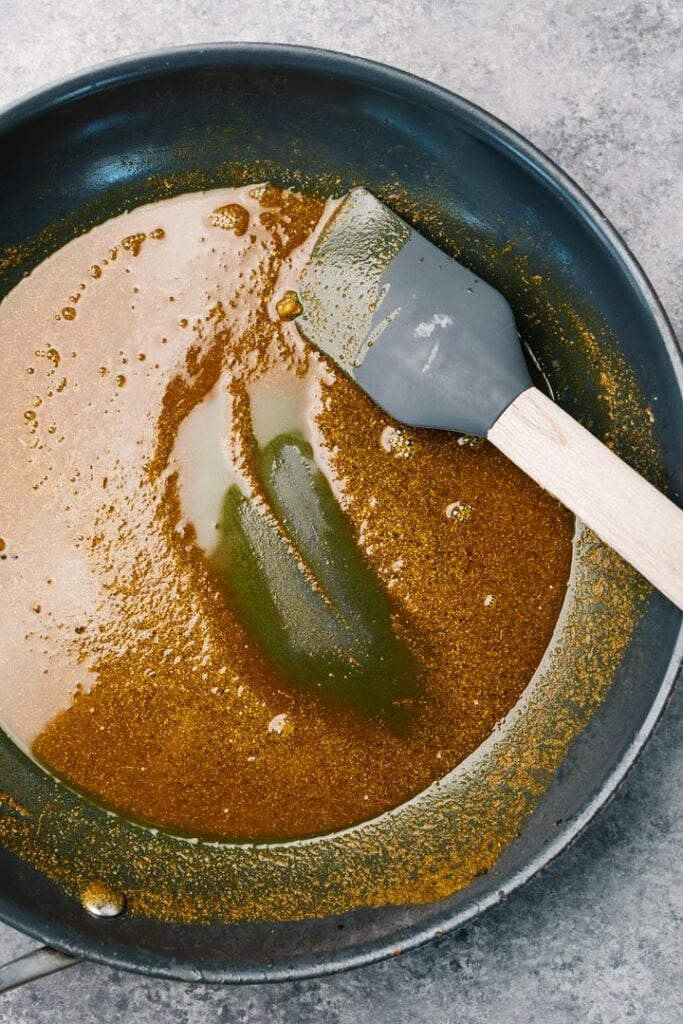 Curry spices toasting in coconut oil in a skillet.