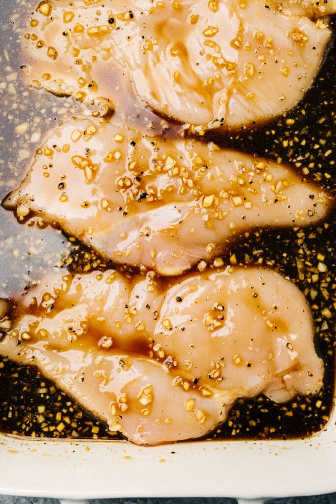 Boneless skinless chicken breasts marinating in teriyaki sauce.