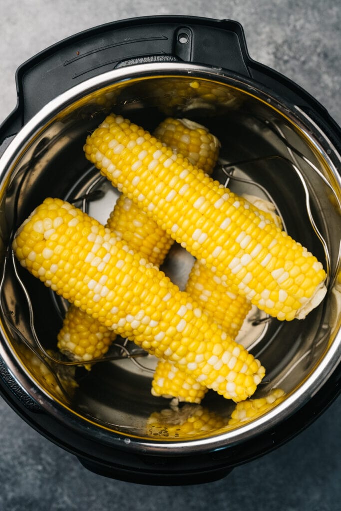 Four ears of cooked corn on the cob layered in an instant pot.